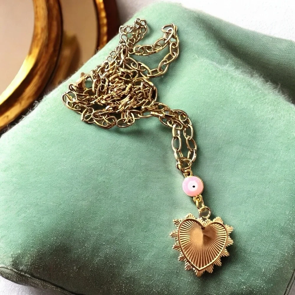 Gold toned chains with black, white, gold, and pastel pink enamel charms.